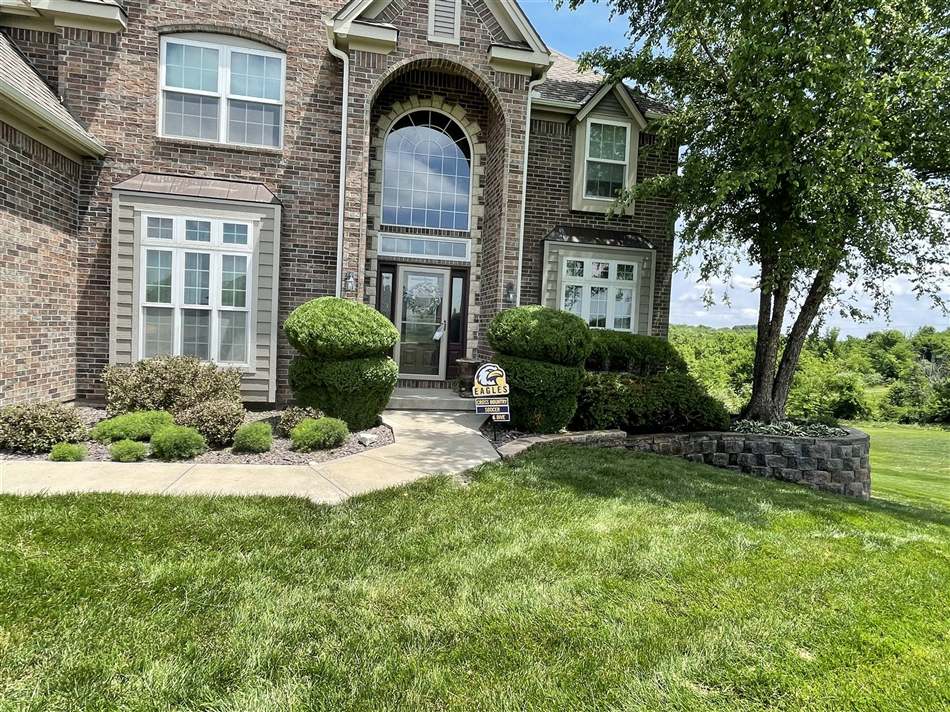 Front landscape with retaining wall, clean lawn, and trimmed greenery